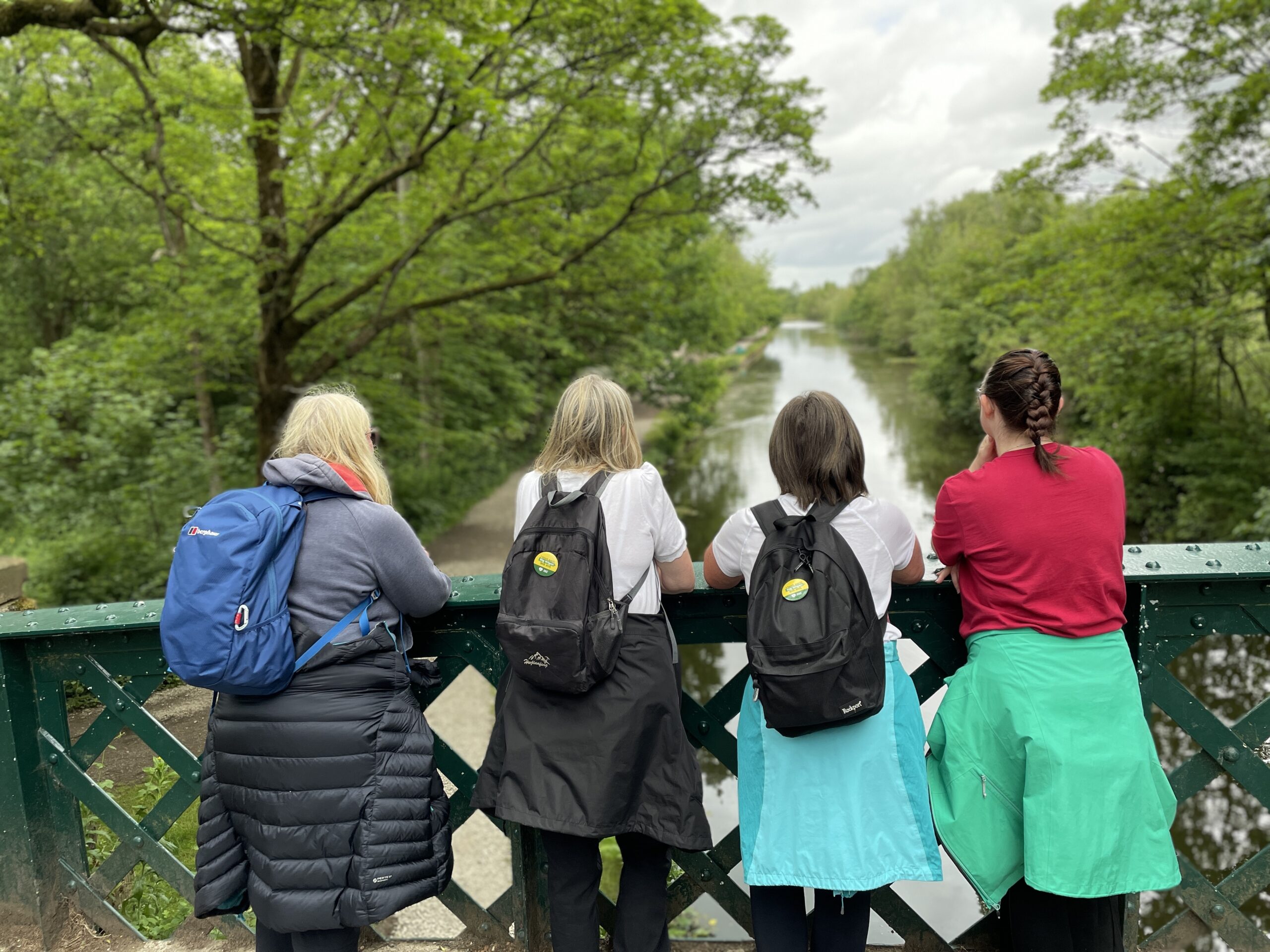 A group of walkers admire the view from a canal bridge at Haigh Woodland Park