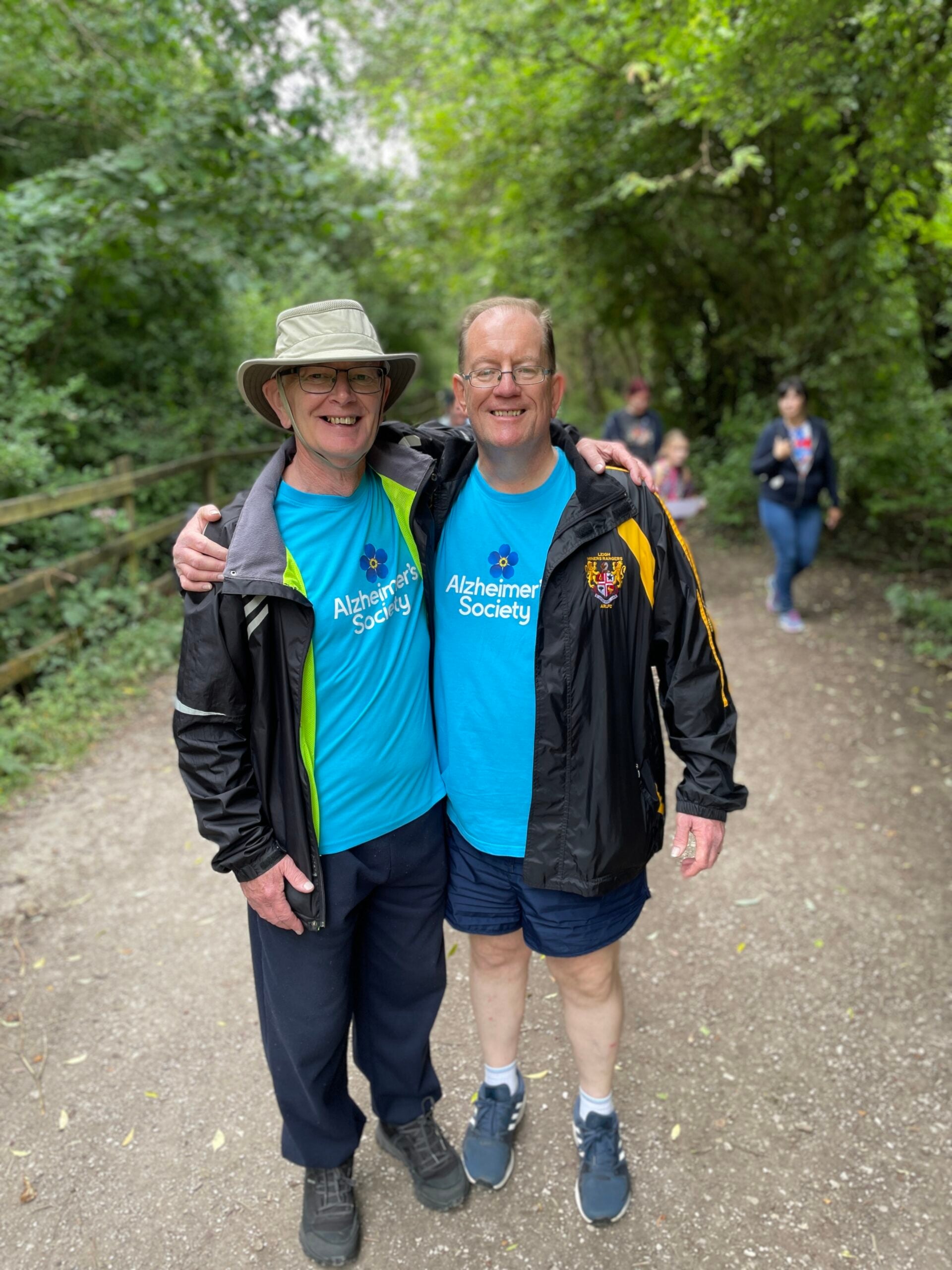 Two men in Alzheimer's Society t-shirts embracing at the Memory Walk